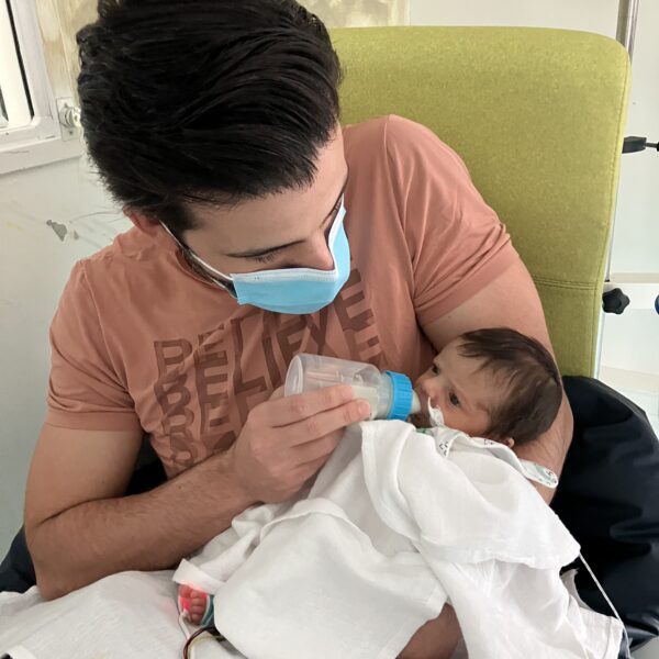 Gabriela's father giving her a bottle in the hospital.